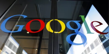 Logo-ul Google pe o ușă de sticlă, reflectând lumina.