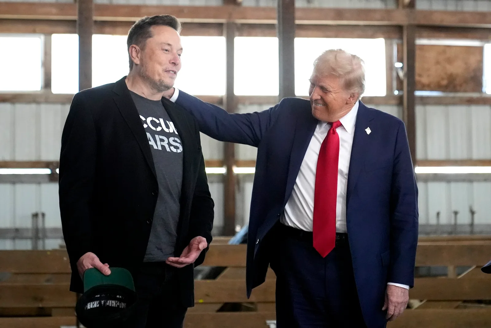 Elon Musk și Donald Trump discutând într-un cadru informal, cu zâmbete pe fețe.