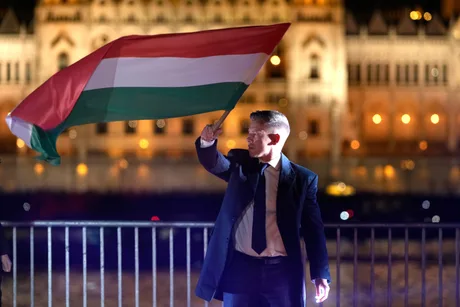 Péter Magyar salută cu steagul Ungariei în fața clădirii Parlamentului.