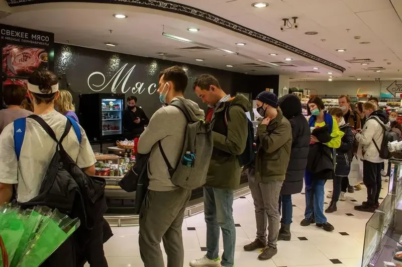 Oameni așteptând la coadă într-un magazin pentru a cumpăra alimente.