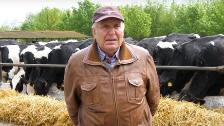 Fermier în fața vacilor de lapte, discutând despre provocările pieței.