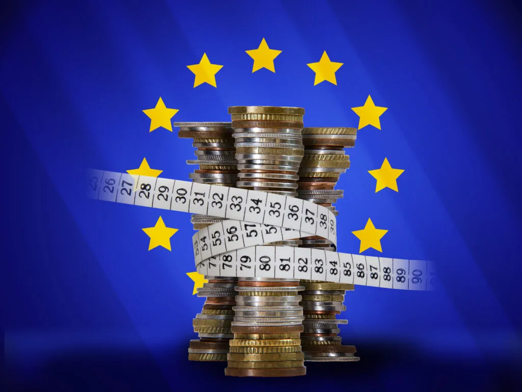 Monede europene stivuite pe fundalul steagului Uniunii Europene.