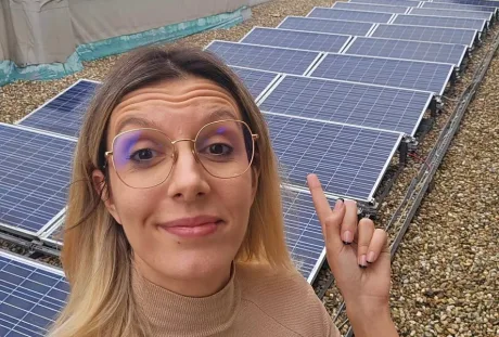 Diana Buzoianu arătând spre panouri solare instalate pe o clădire.