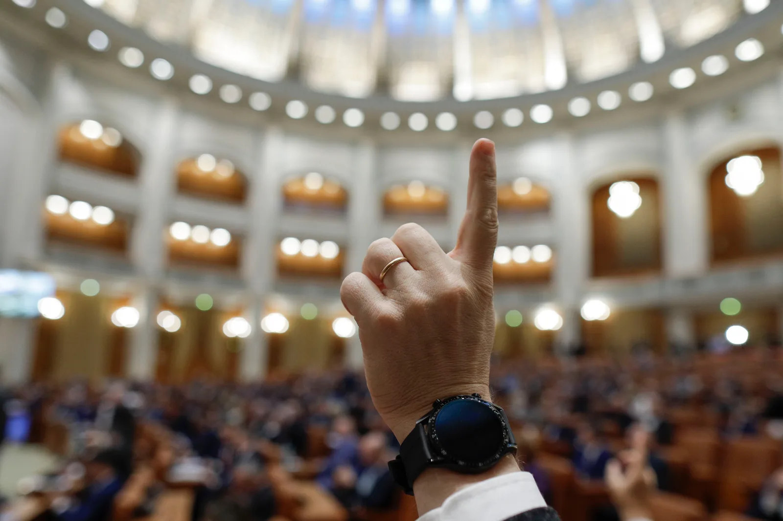 Un senator ridică degetul într-o sesiune plenară a Senatului României.