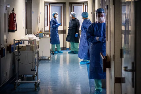 Personal medical discutând într-un spital, în uniformă de protecție.