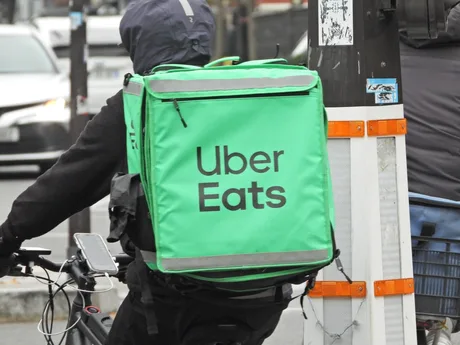 Curier Uber Eats livrând mâncare pe o bicicletă în oraș.