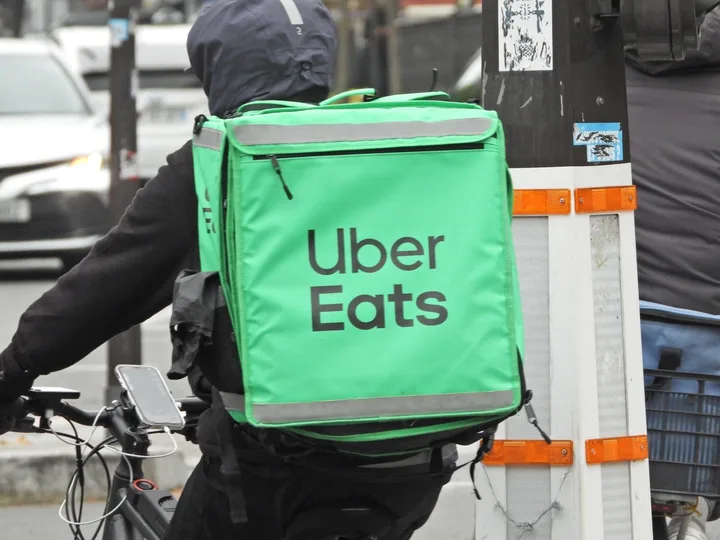 Curier Uber Eats livrând mâncare pe o bicicletă în oraș.