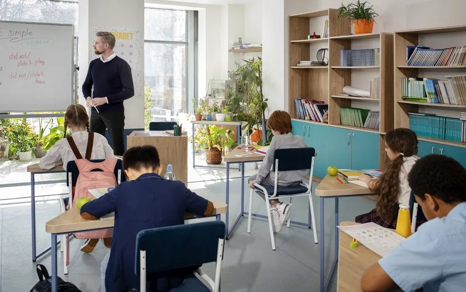Elevi la ore, învățând în clasă, cu un profesor la tablă.
