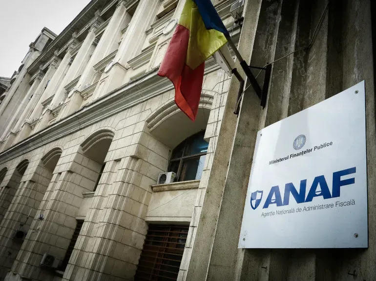 Sediul ANAF cu drapelul României în față, simbol al administrației fiscale.