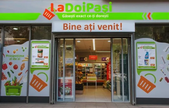 Intrarea unui magazin LaDoiPași, cu produse expuse și mesaje de bun venit.