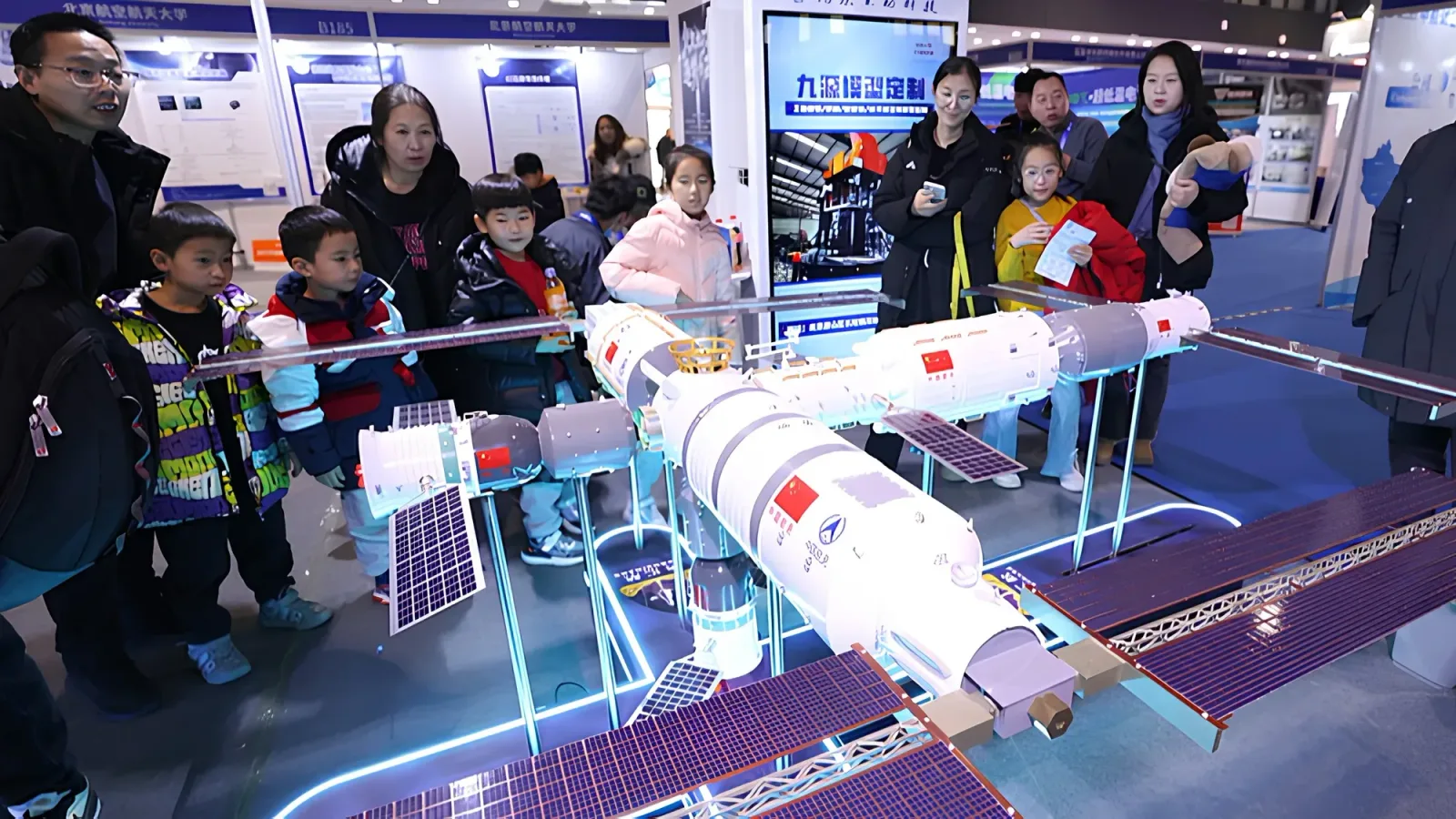 Vizitatori admirând un model al stației spațiale Tiangong la un eveniment public.