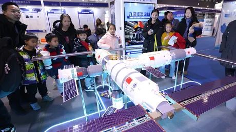 Vizitatori admirând un model al stației spațiale Tiangong la un eveniment public.