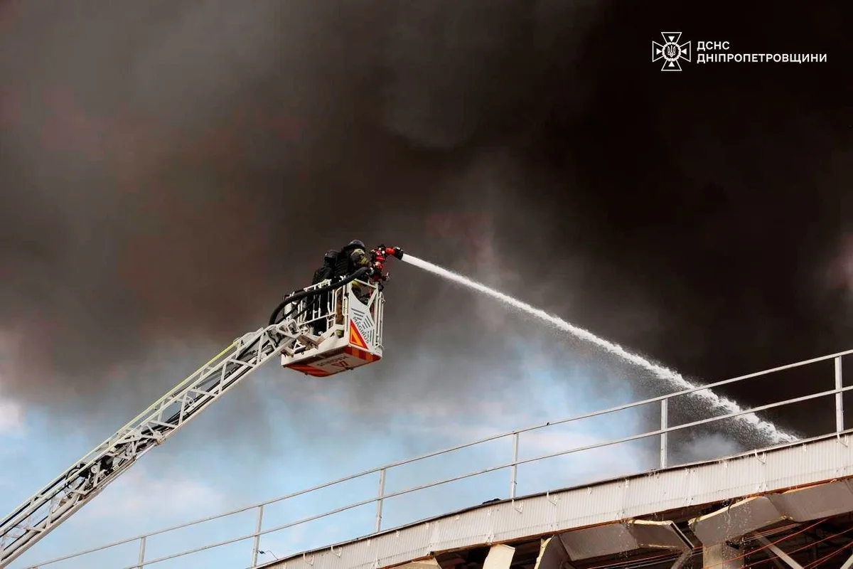 Intervenție a pompierilor pentru stingerea incendiului într-o zonă industrială afectată.