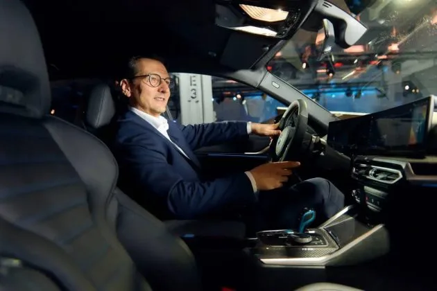 Un bărbat la volanul unei mașini BMW într-un interior modern.