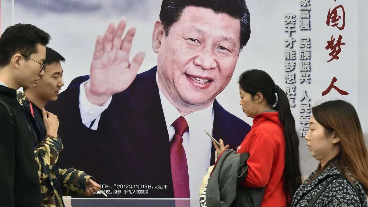 Oameni care discută în fața unui panou publicitar cu un lider chinez.