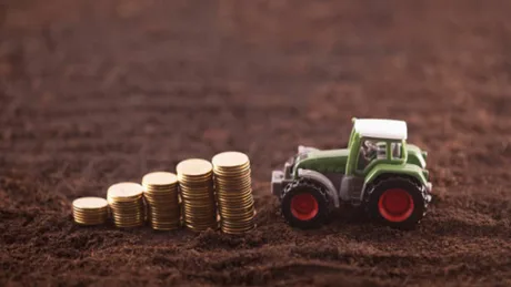 Tractor pe câmp, simbolizând subvențiile pentru fermieri.
