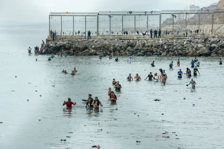 Migranți înotând în apă, încercând să ajungă în Ceuta.