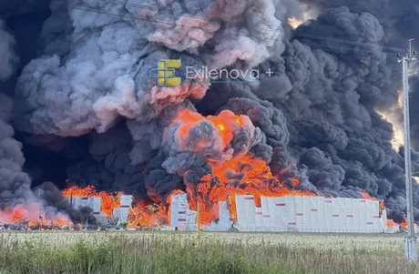 Incendiu masiv la un depozit, cu fum și flăcări uriașe în fundal.