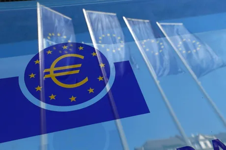Steaguri ale Uniunii Europene reflectate pe o suprafață de sticlă.