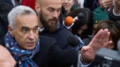 Călin Georgescu vorbește în fața presei, înconjurat de susținători.