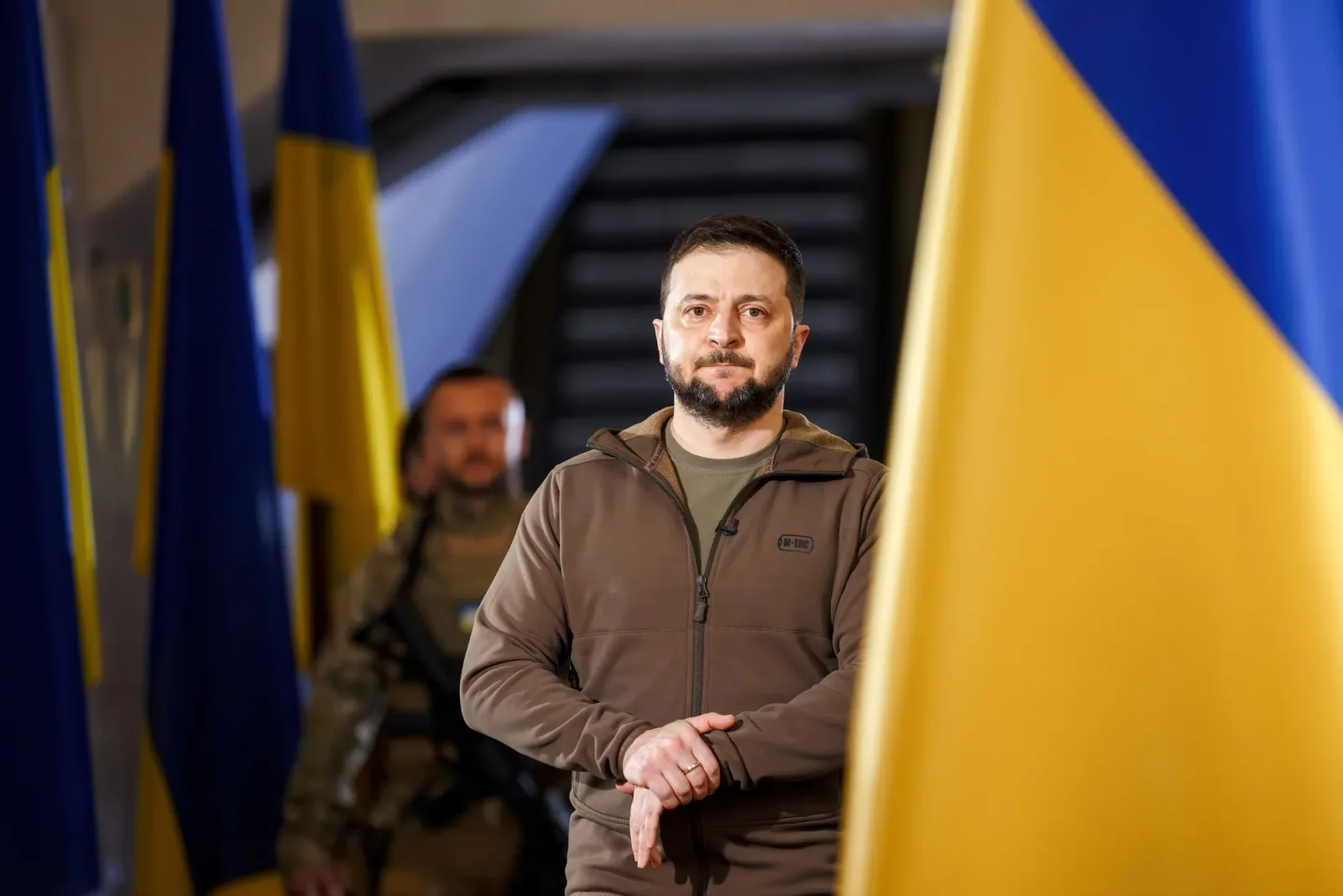 Zelenski în fața steagurilor ucrainene, într-un context militar.