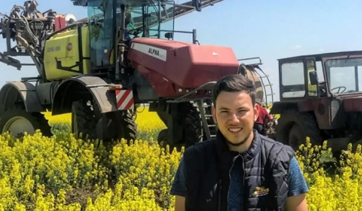 Fermier în rapiță, cu recolta bogată în fundal, pe un câmp înflorit.