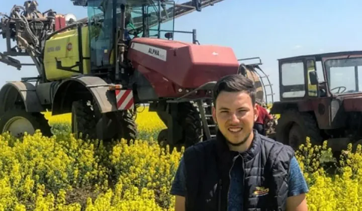 Fermier în rapiță, cu recolta bogată în fundal, pe un câmp înflorit.