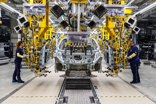 Linie de asamblare BMW cu muncitori la lucru în fabrică.