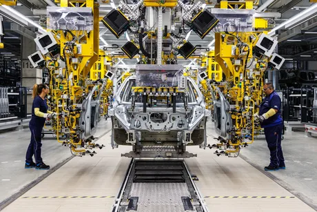 Linie de asamblare BMW cu muncitori la lucru în fabrică.