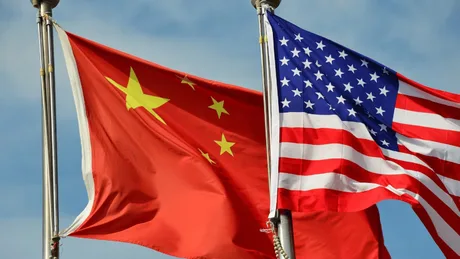 Steagurile Chinei și SUA fluturând în vânt, simbolizând tensiuni internaționale.