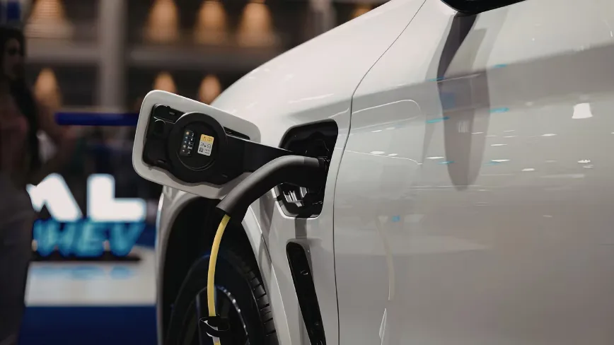 Mașină electrică conectată la o stație de încărcare, simbol al tranziției ecologice.