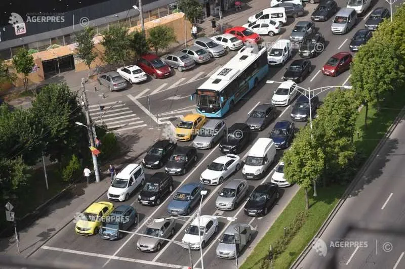 Trafic aglomerat pe o stradă din oraș, cu diverse tipuri de autovehicule.