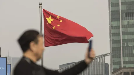 Steagul Chinei fluturând în fața unui peisaj urban modern.