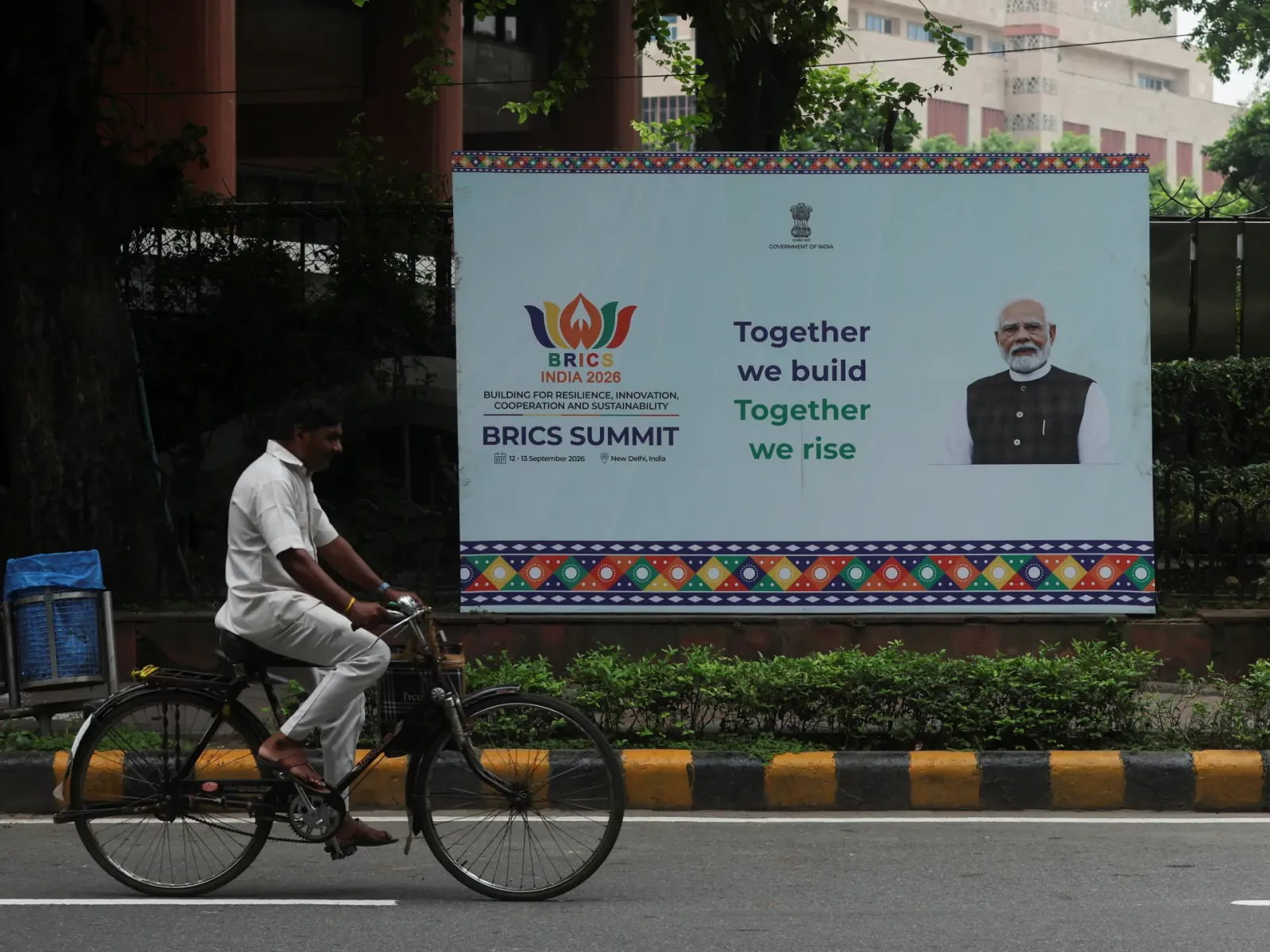 Un bărbat pe bicicletă trece pe lângă un banner al summitului BRICS la New Delhi.