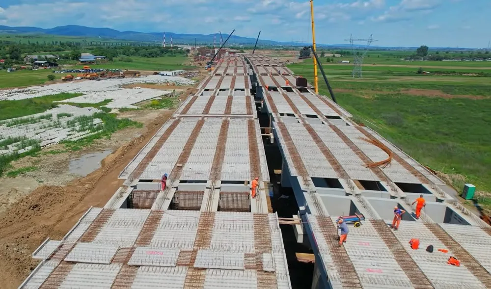 Lucrări pe șantierul autostrăzii A7 Răcăciuni–Bacău, cu muncitori și utilaje în acțiune.