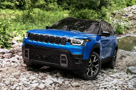 Un model Jeep albastru parcurs pe un teren accidentat, pregătit pentru export.