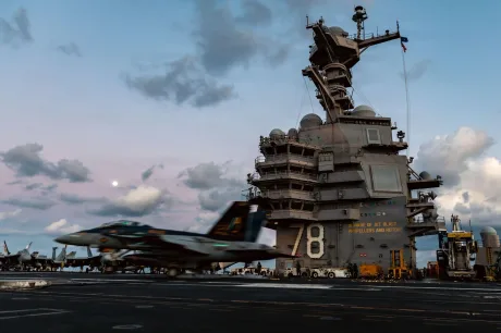 Nava militară americană în acțiune pe mare, cu cer senin și nori pufoși.