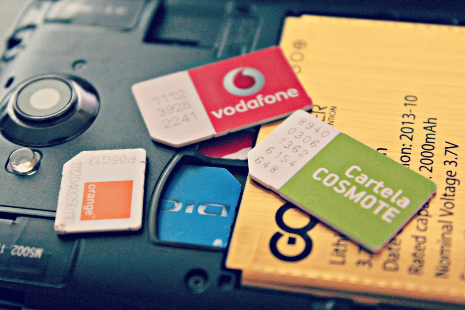 Cartela SIM de la diferiți operatori telecom pe un telefon mobil.