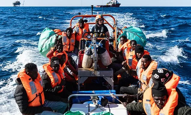 Refugiați pe o barcă, purtând veste de salvare, pe mare.
