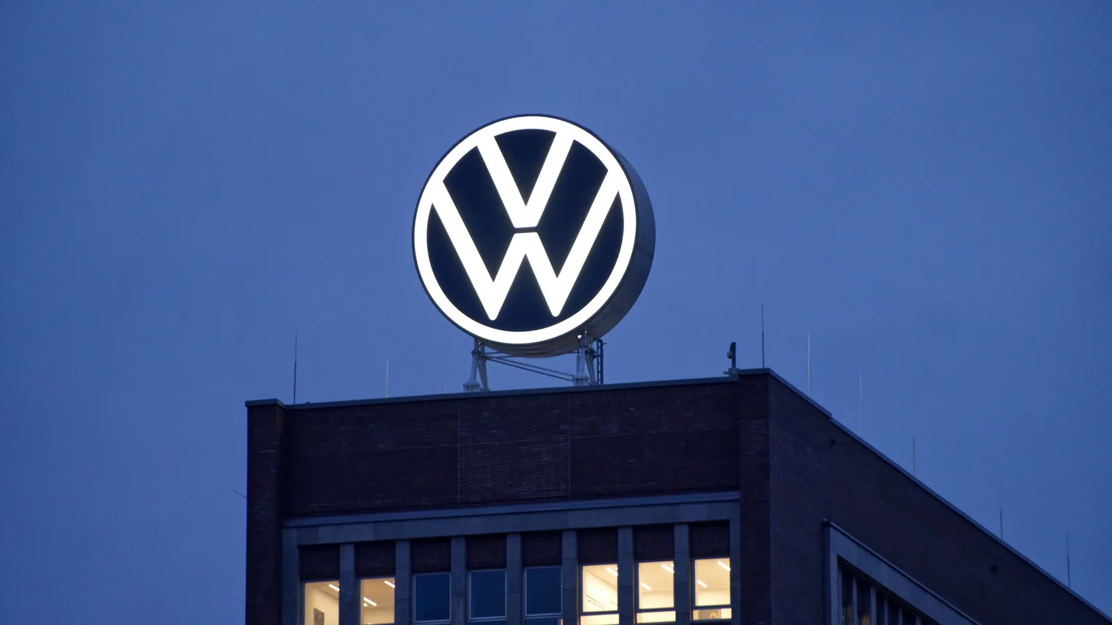 Sigla Volkswagen iluminată pe un clădire în timpul nopții.