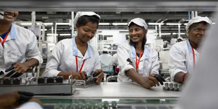 Angajați la o fabrică de componente electronice din India, zâmbind în timpul lucrului.