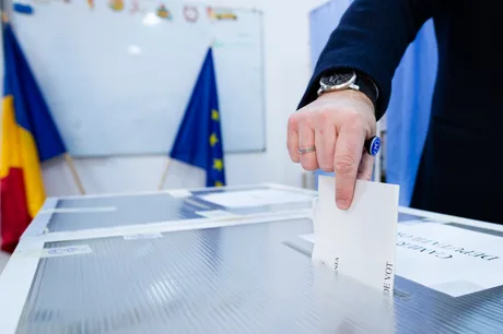 Un alegător depune un buletin de vot într-o urnă electorală.