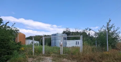Instalație de apă în comuna Berlești, Gorj, cu vegetație abundentă în jur.