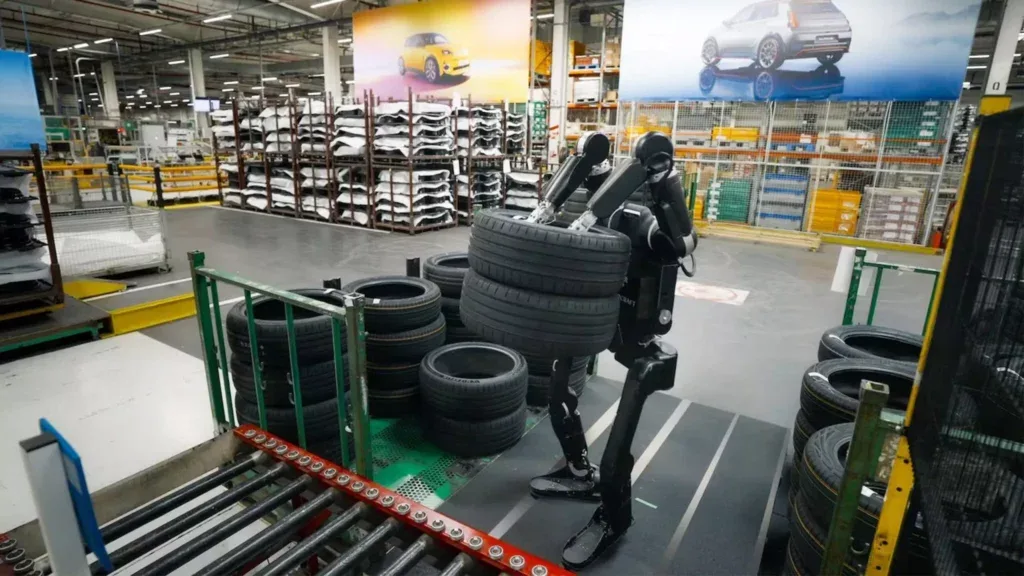 Robot humanoid manipulând anvelope într-o uzină auto