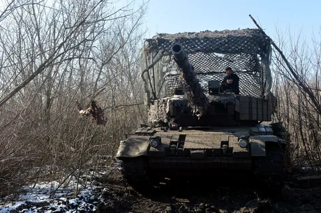 Tanc Leopard 1A5 camuflat în pădure, pregătit pentru acțiune.