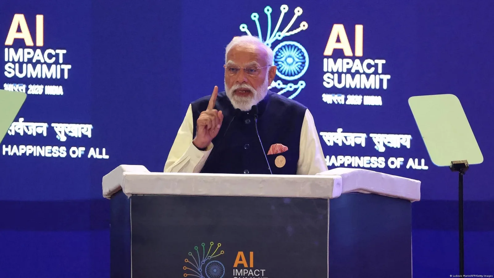 Premierul indian Narendra Modi vorbește la summitul AI din Delhi, cu lideri tehnologici în fundal.