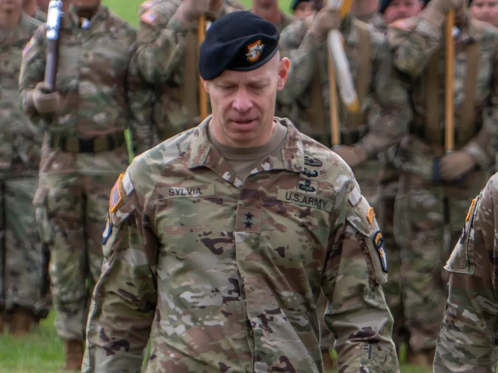 Generalul Brett Sylvia părăsește o ceremonie militară, înconjurat de soldați.