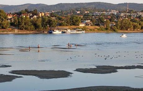 Peisaj fluvial cu oameni pe malul Dunării în timpul secetei.