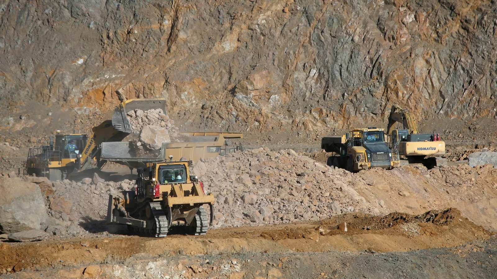 Utilaje grele extrag minerale dintr-o carieră de piatră.