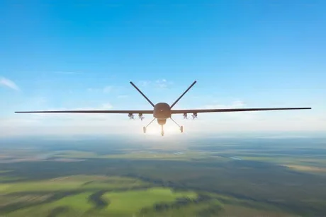 Drone zburând deasupra unui peisaj rural, avertizare de securitate.